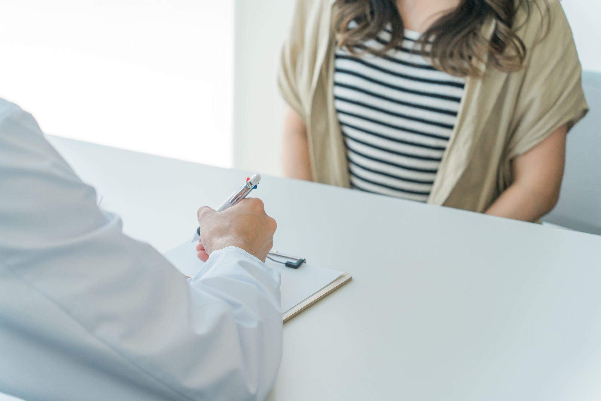 診察を受ける患者の女性と話を聞く医師