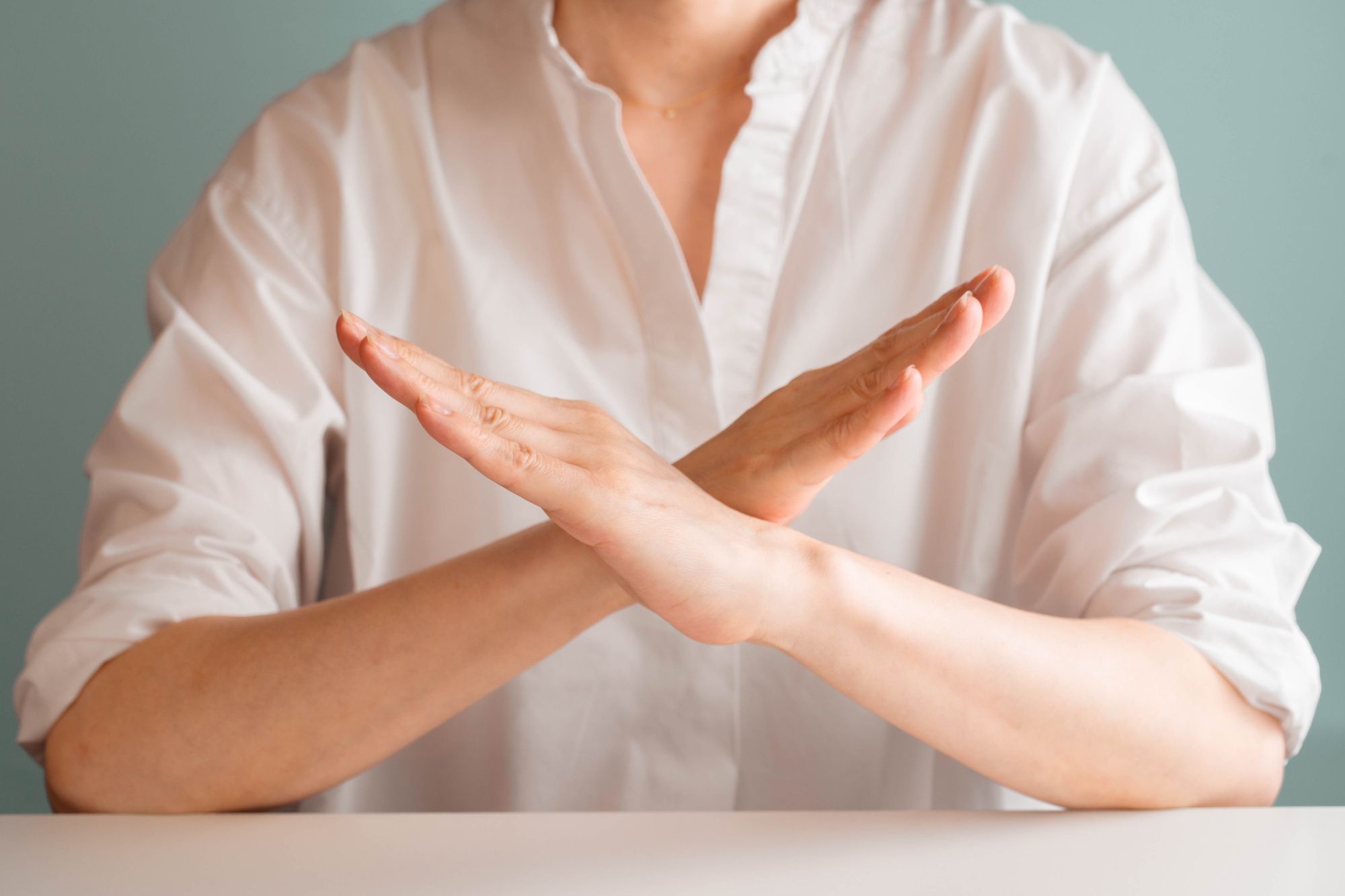 腕でバツマークを作る女性