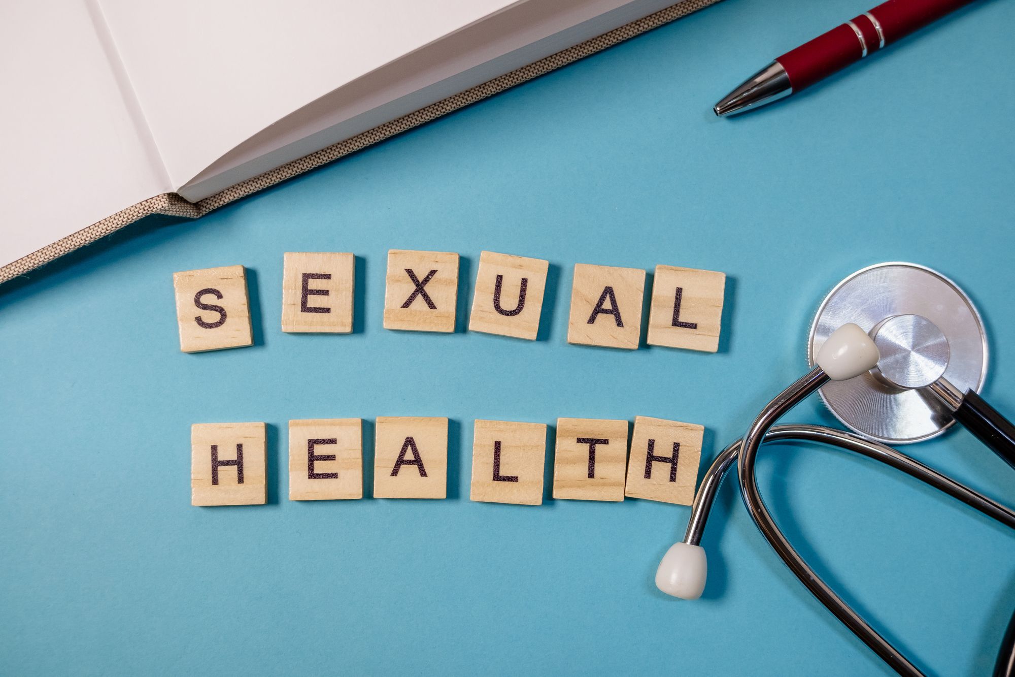 SEXUAL HEALTHの文字と聴診器、ペン、ノートのおかれたデスク
