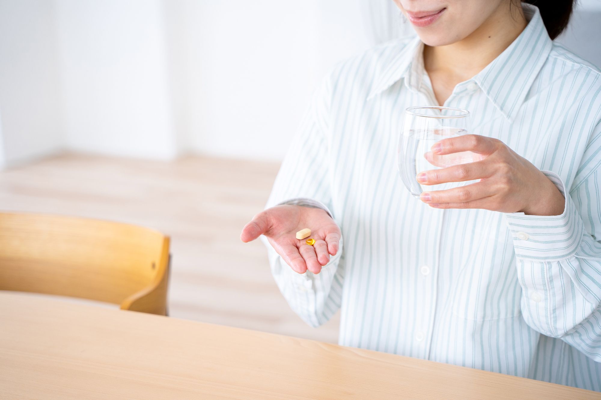 テーブルで薬を飲む女性