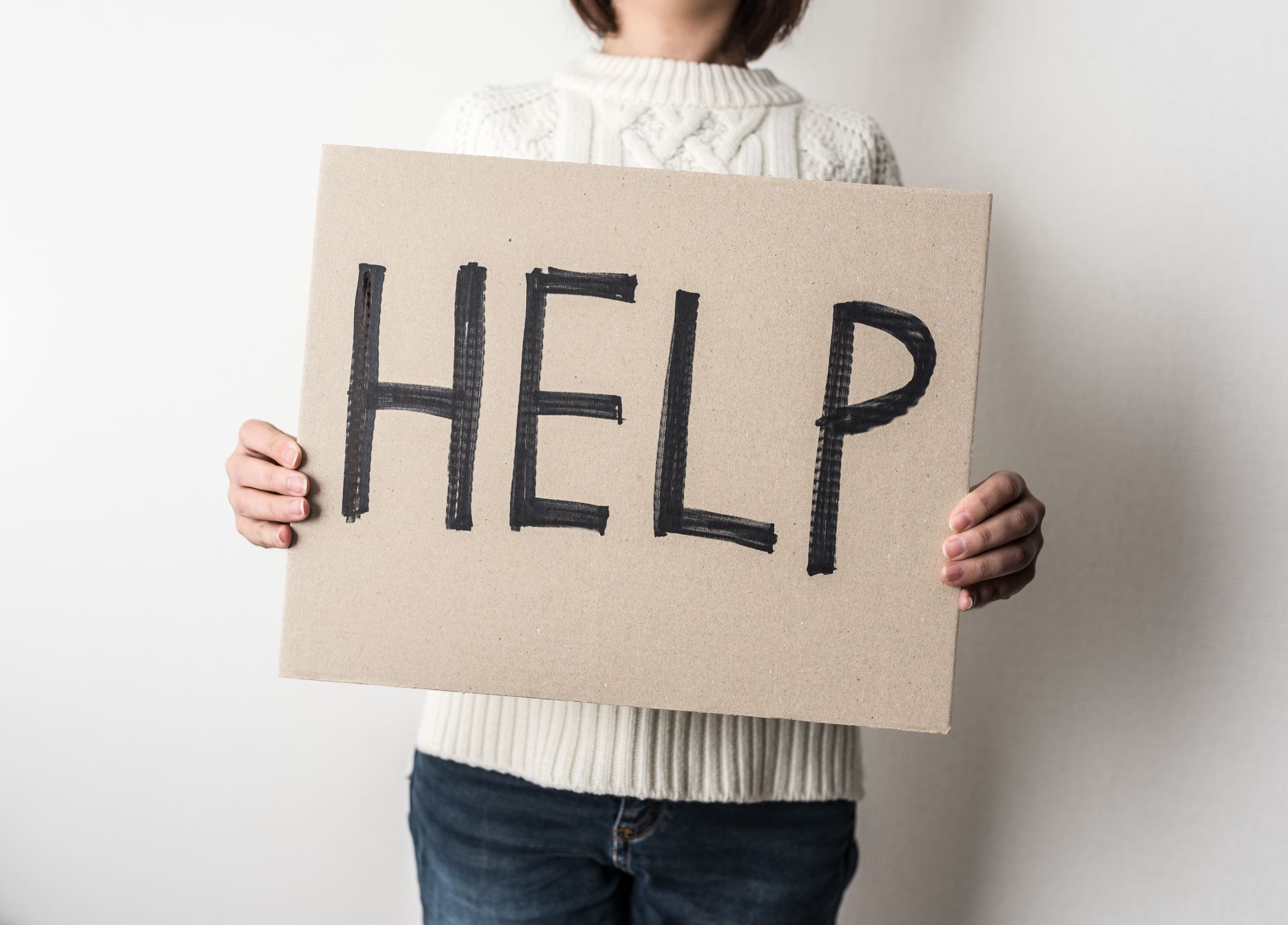「HELP」の看板を掲げる女性
