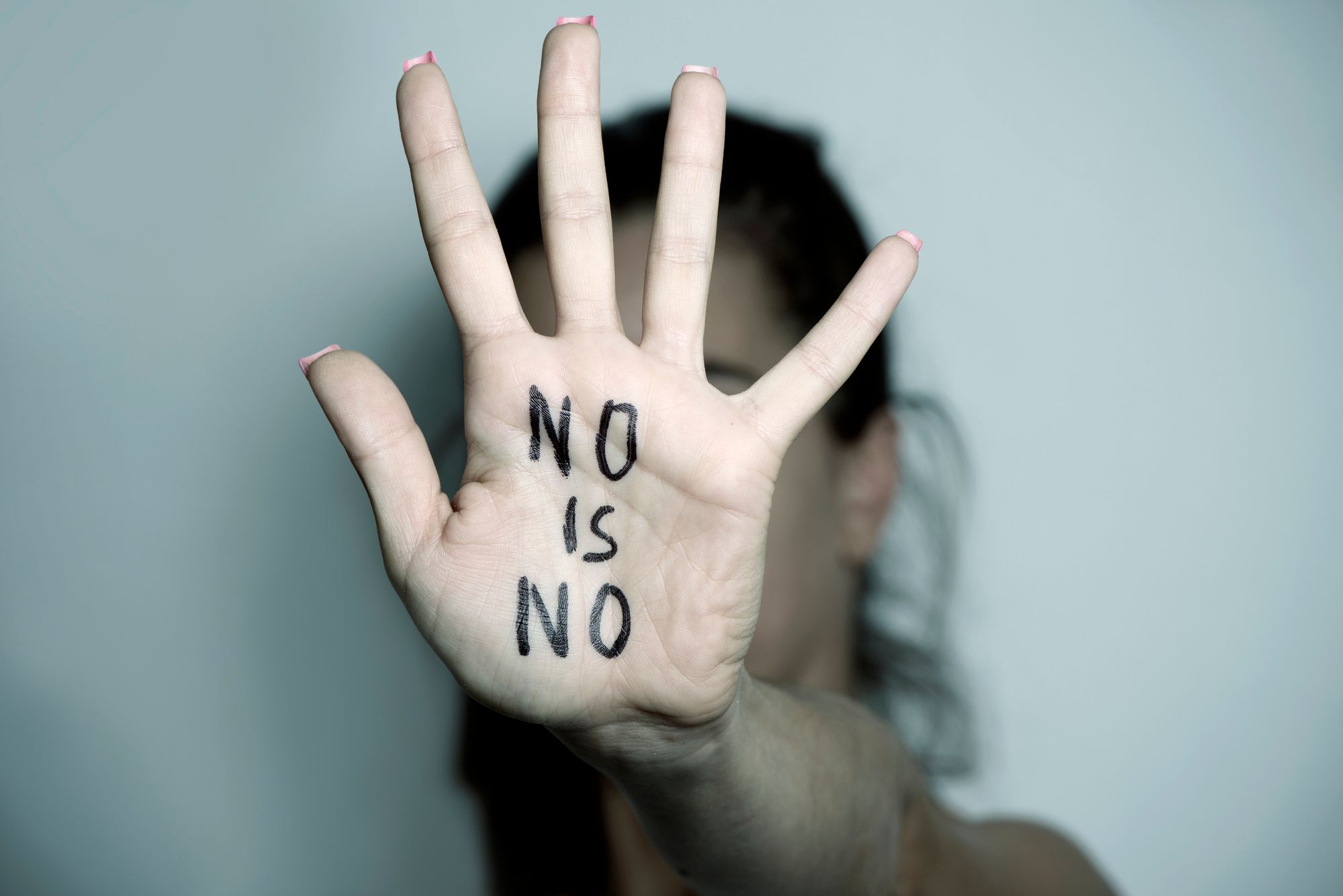 NO is NOと書かれた手をかざす女性