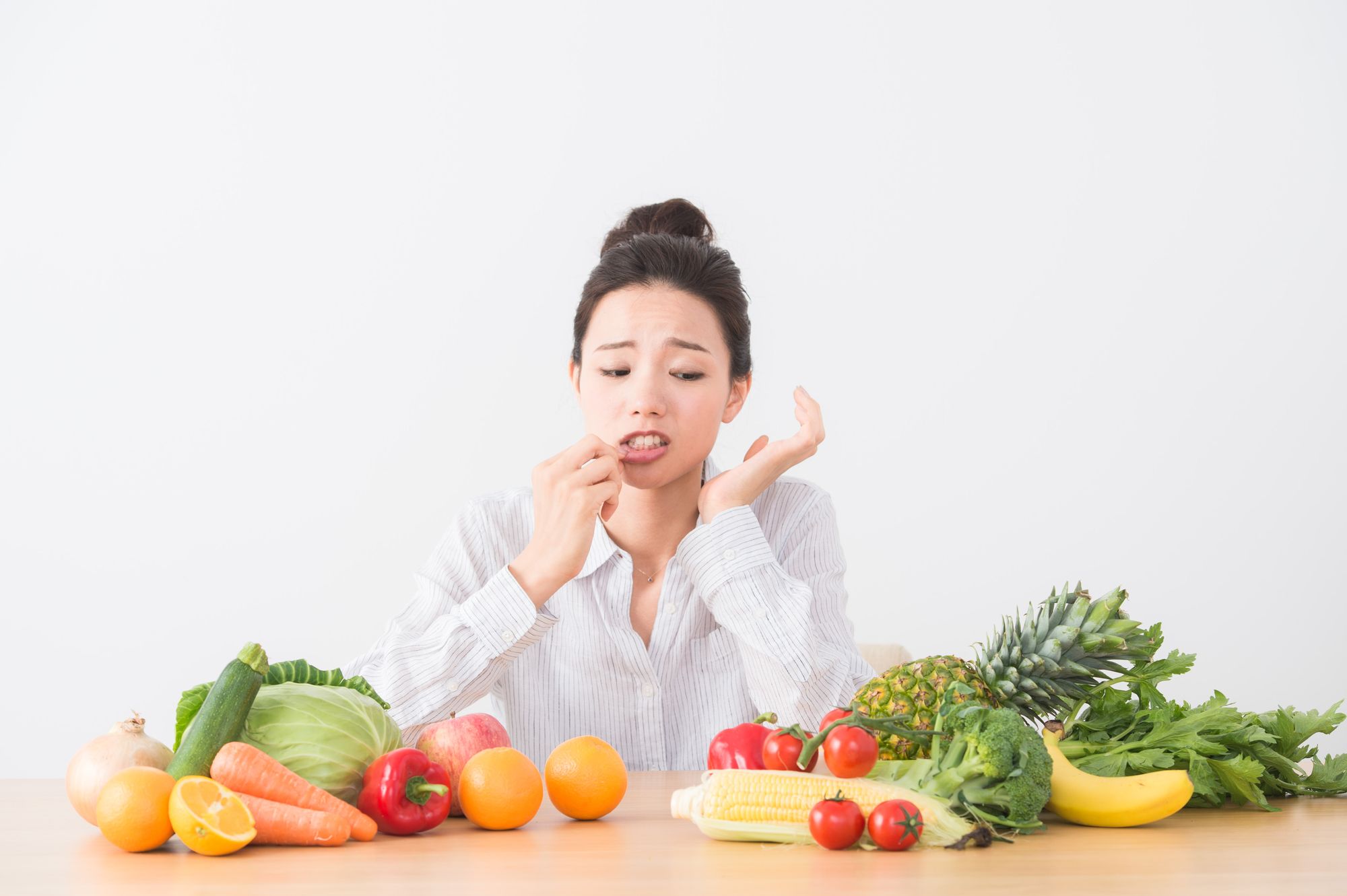 テーブルに置かれた野菜と口内炎の女性