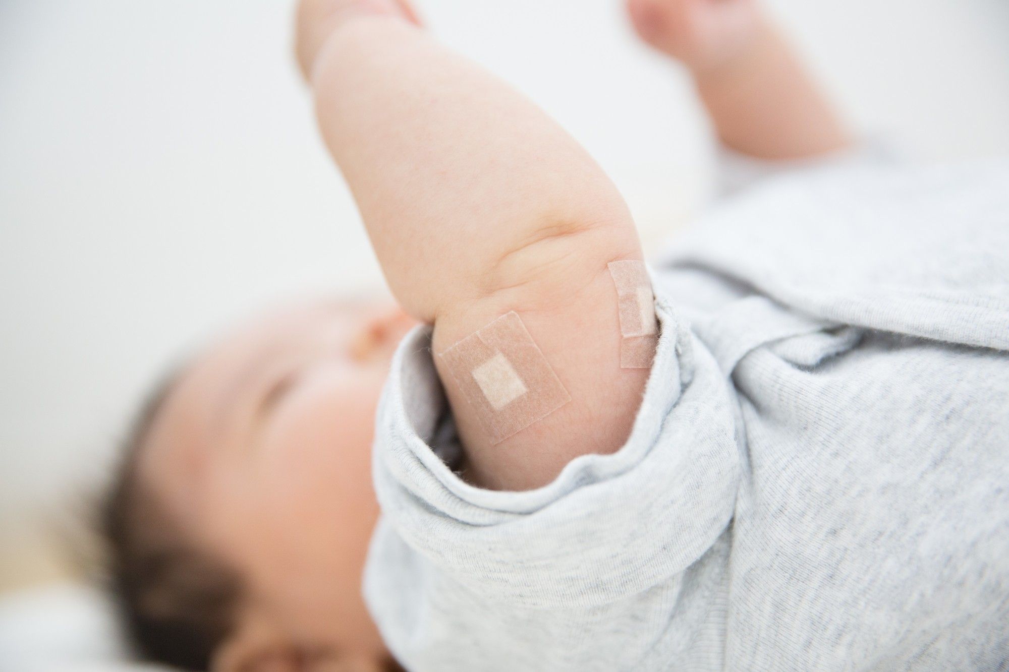 予防接種後で腕にばんそうこうを貼った赤ちゃん