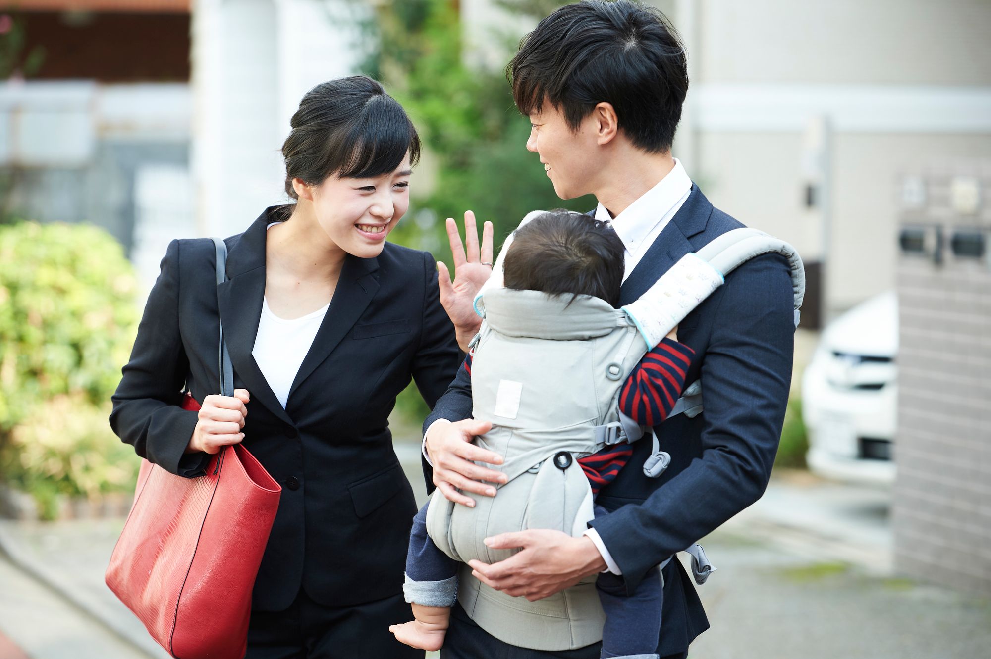 スーツ姿のお母さんと、抱っこ紐で子供を抱えたお父さん