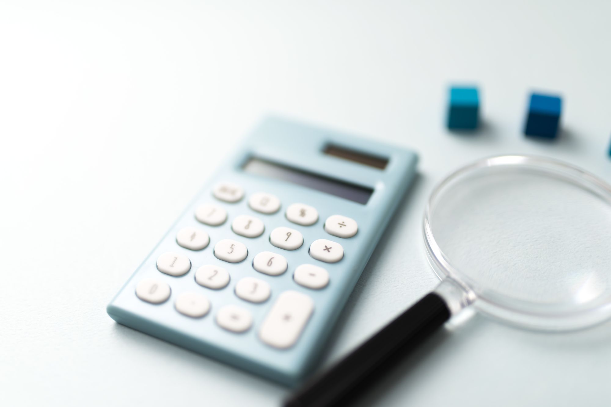 電卓と虫メガネの写真