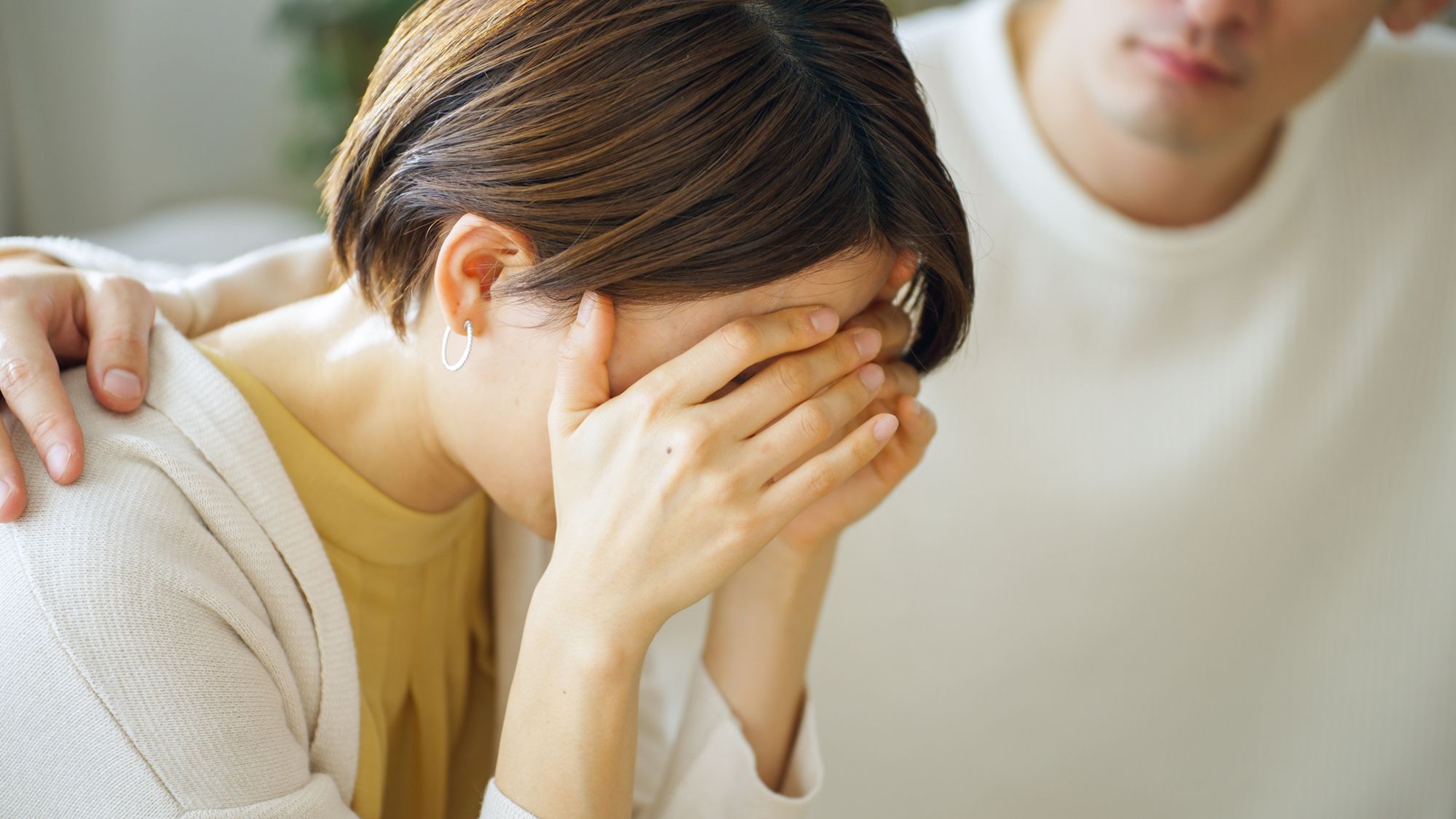 泣く女性の肩に手を載せて励ます男性パートナー