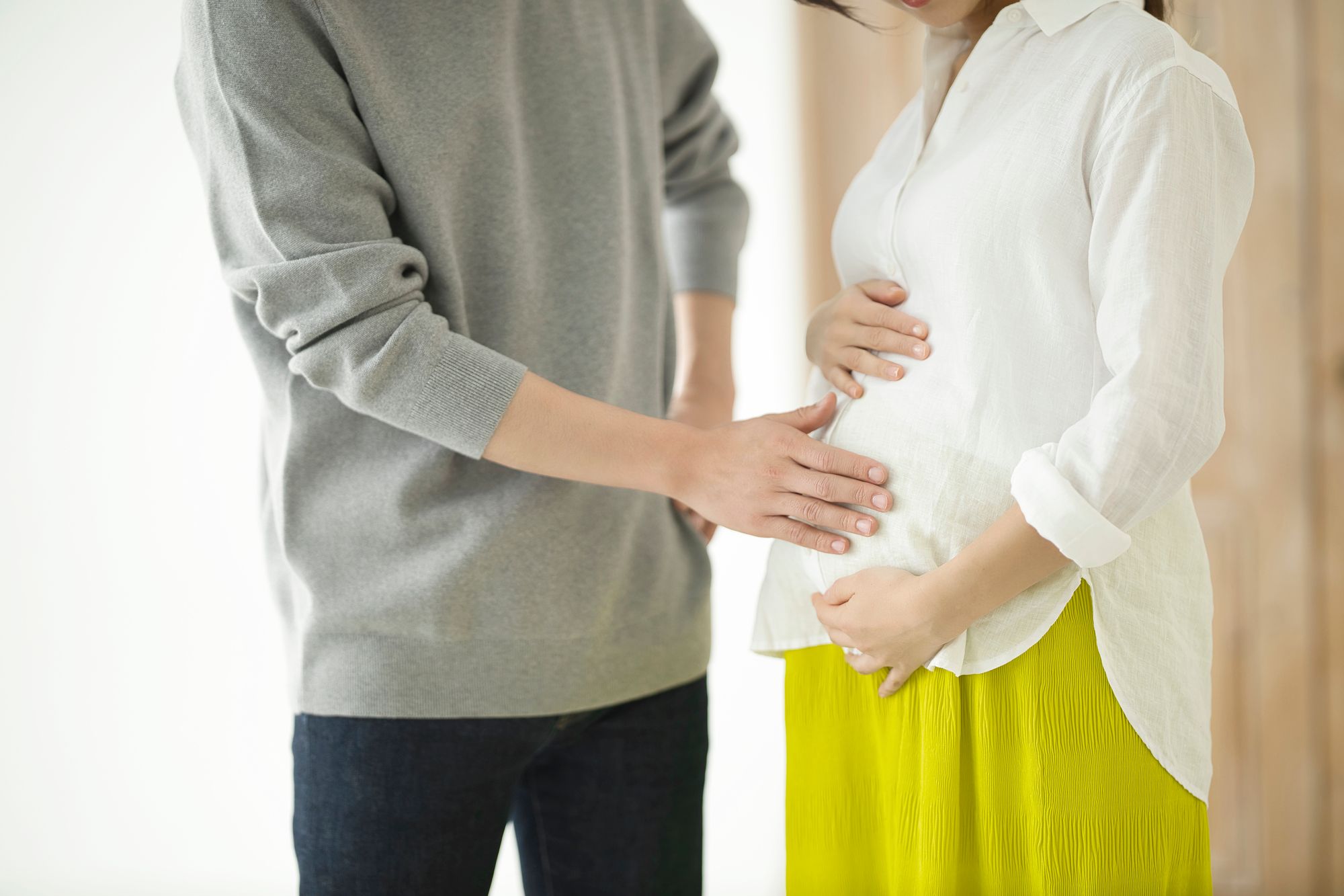 妊婦のおなかに手を添えて話す夫婦